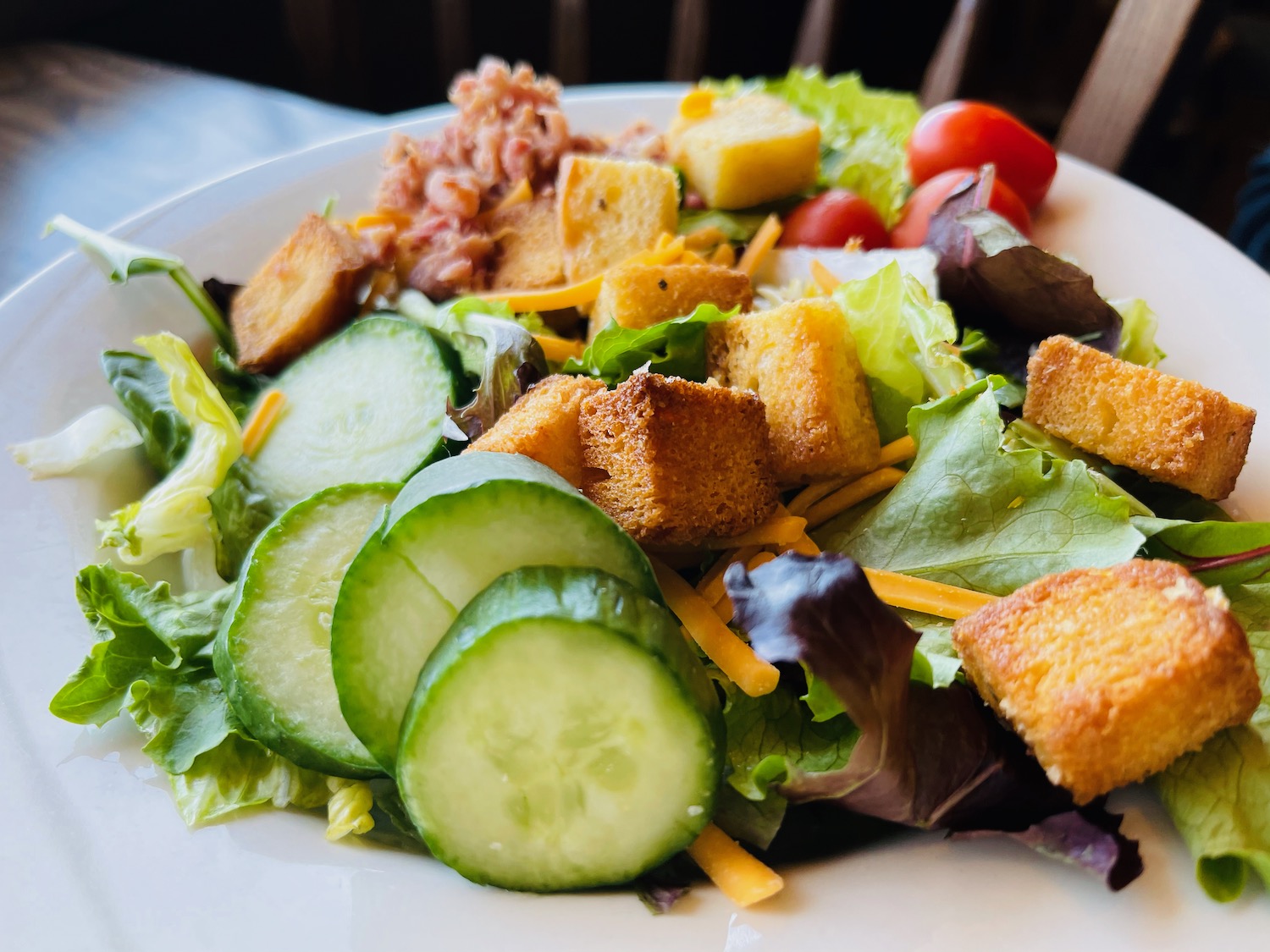 a plate of salad with croutons and cucumbers