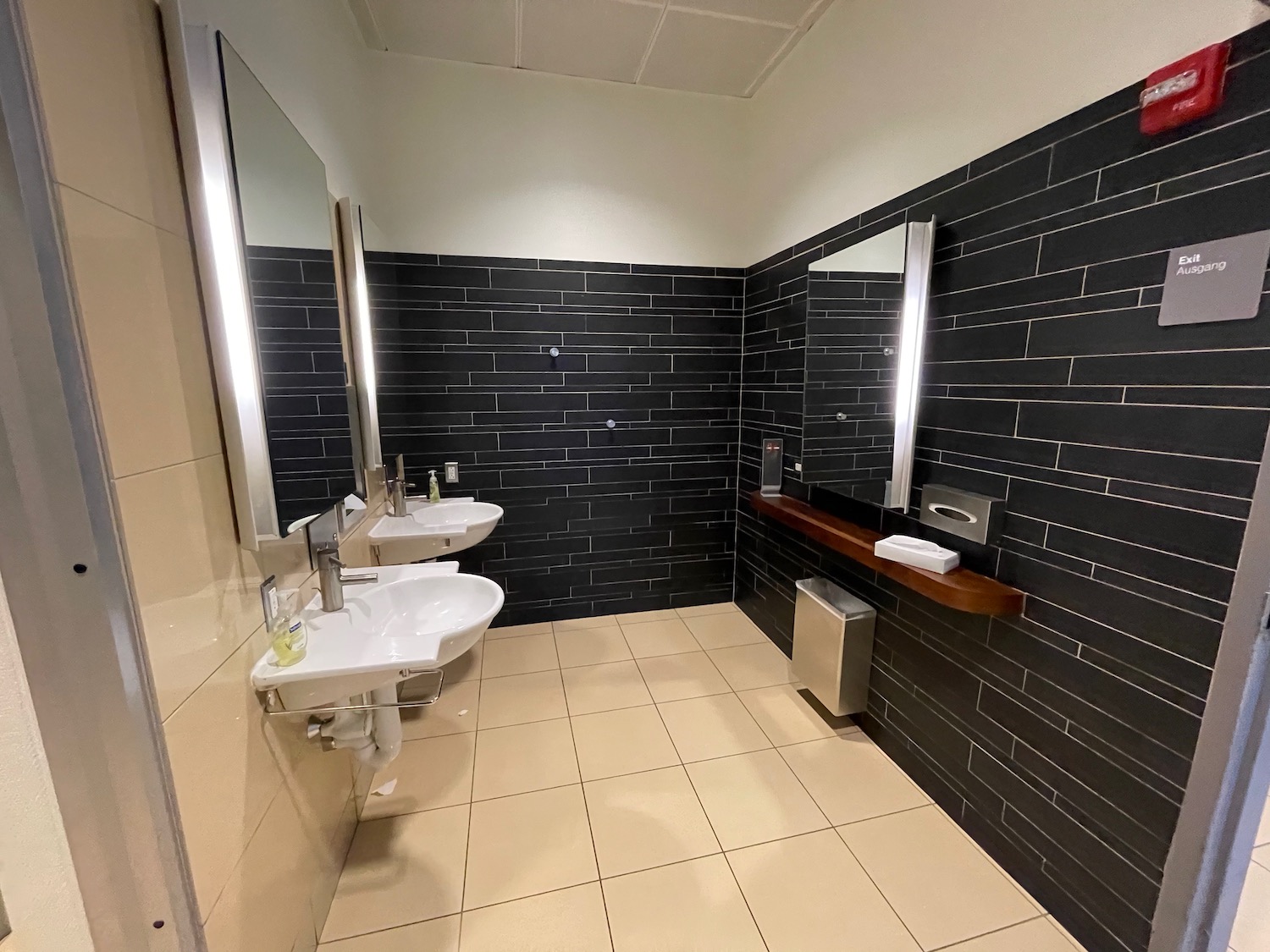 a bathroom with black tile walls and sinks