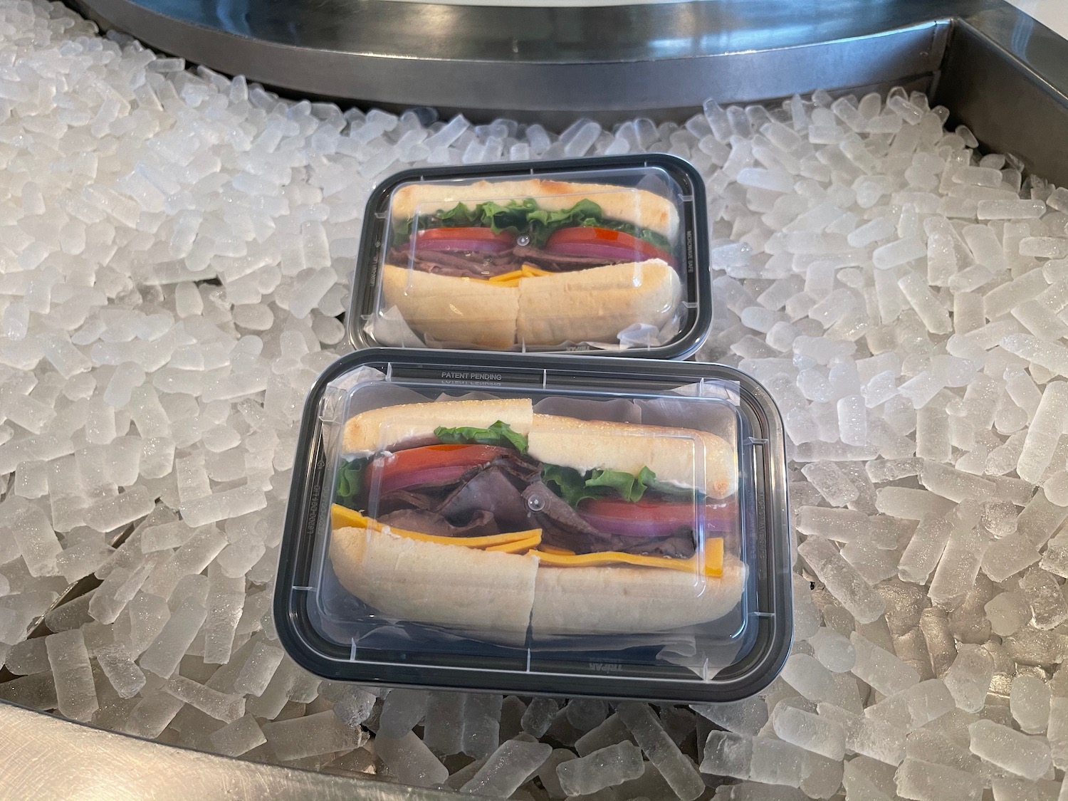 two plastic containers of sandwiches on ice