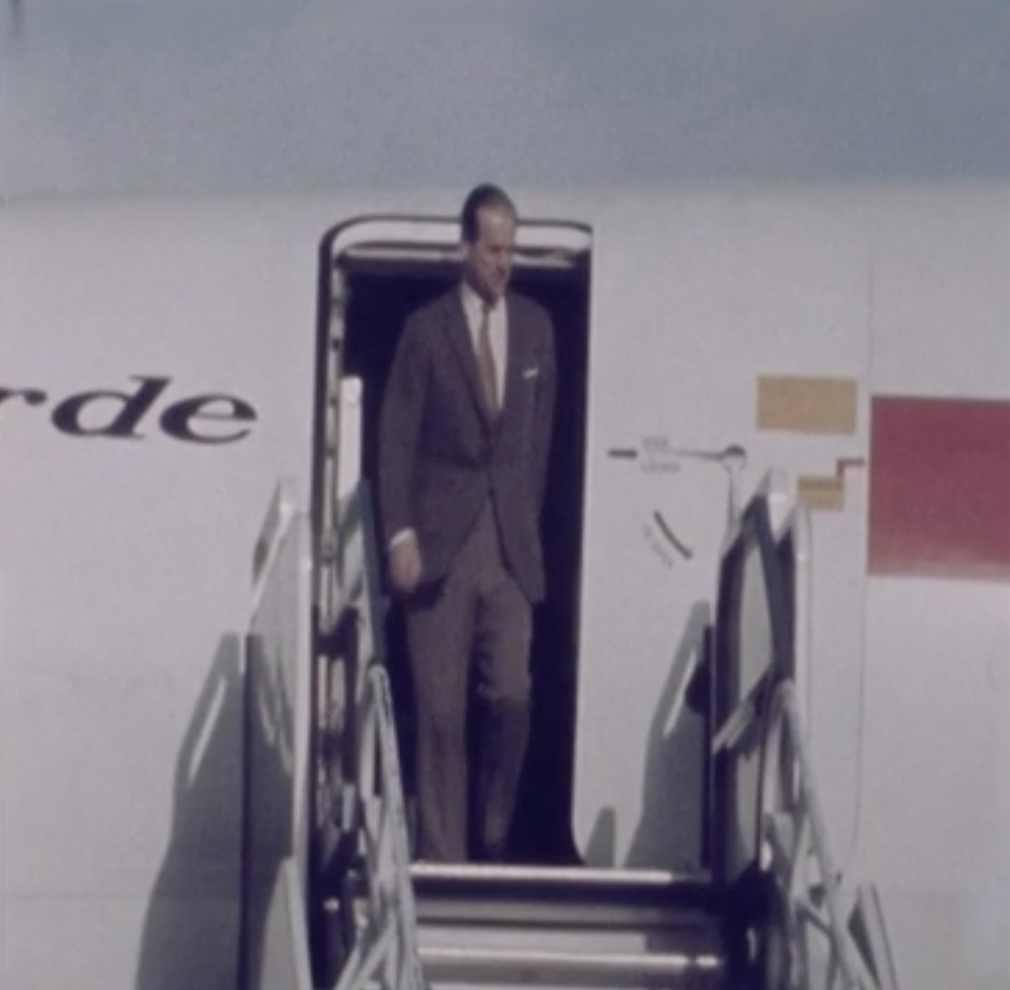 a man in a suit walking out of an airplane