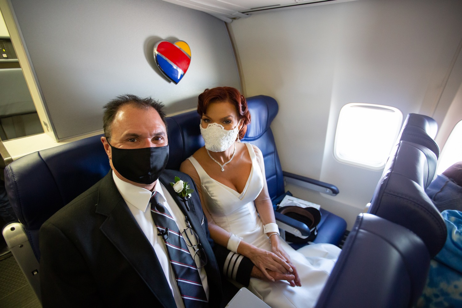 a man and woman wearing face masks sitting in a plane