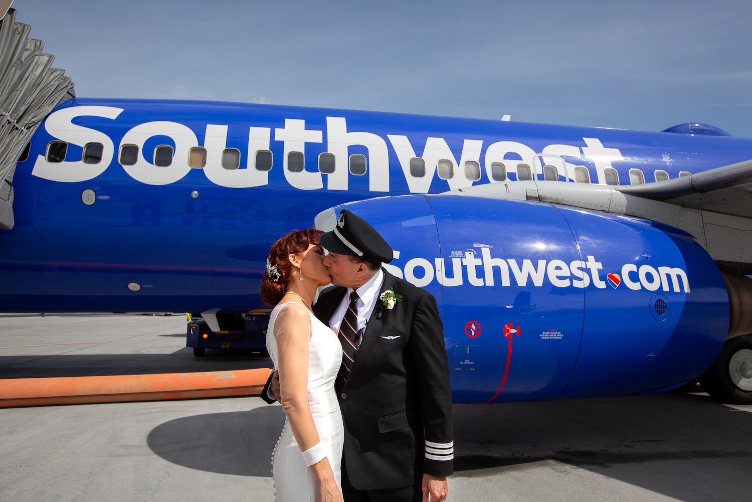 a man and woman kissing in front of a plane