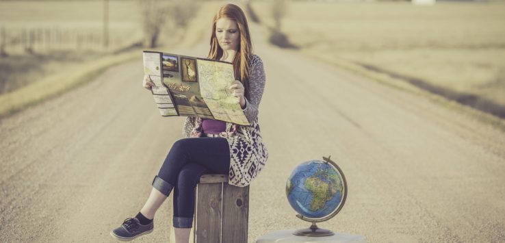 a woman sitting on a box looking at a map