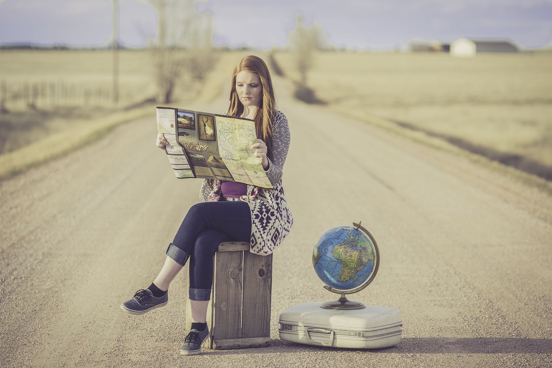 a woman sitting on a box looking at a map