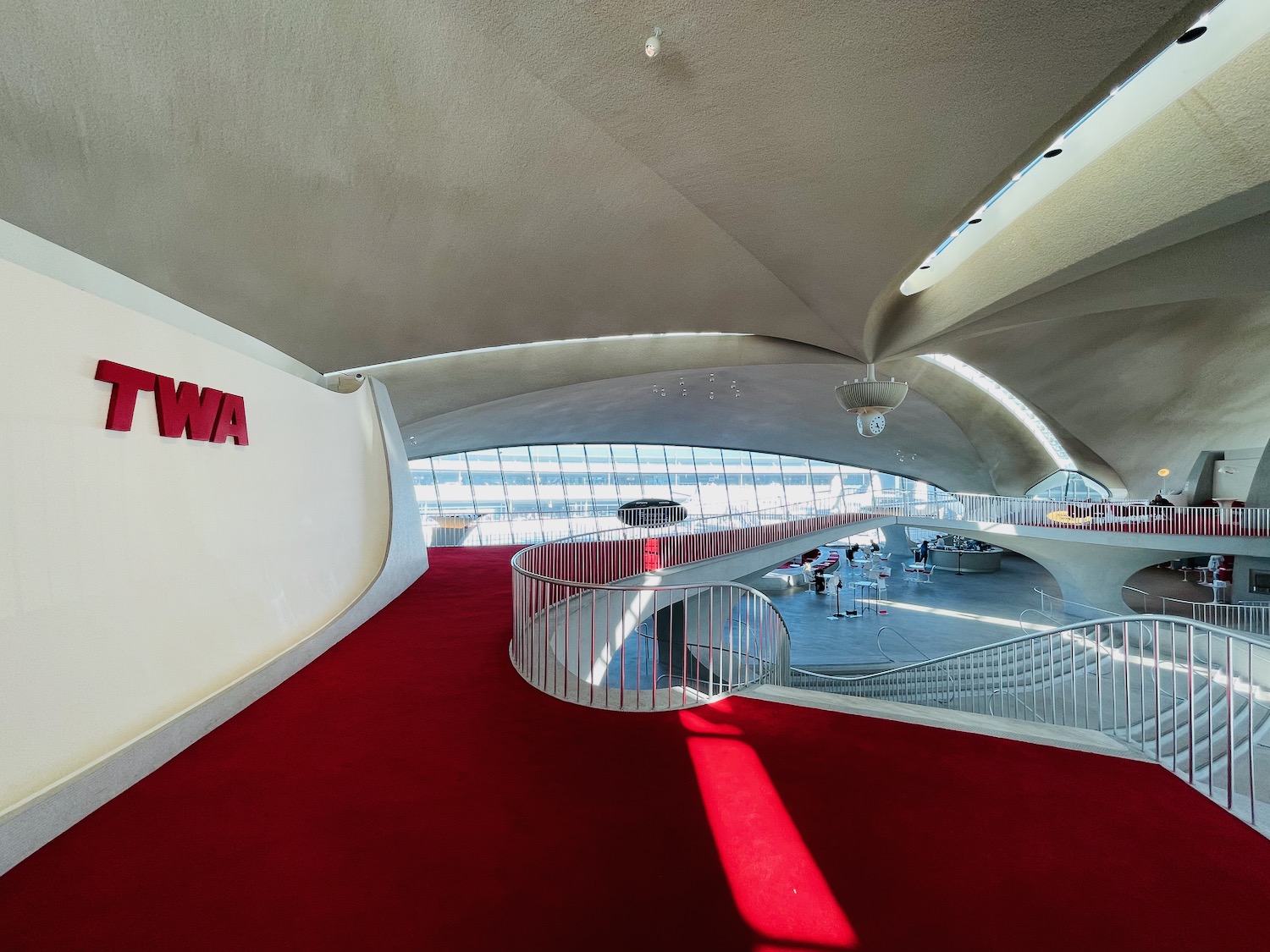 a red carpeted hallway with a staircase and a sign