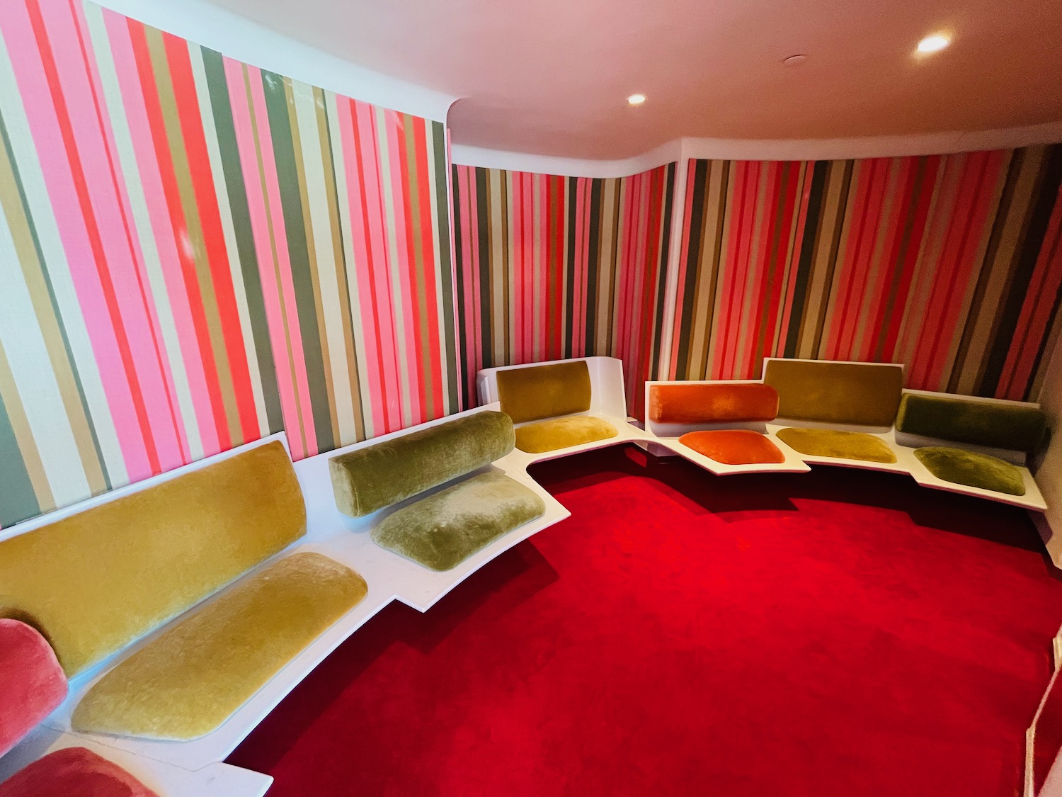 a room with colorful striped walls and a red carpet