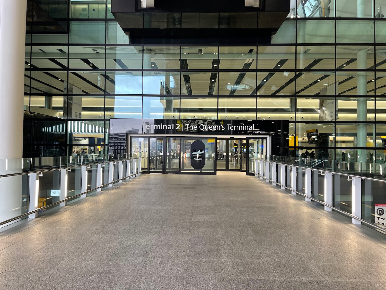 a glass building with a walkway and a sign