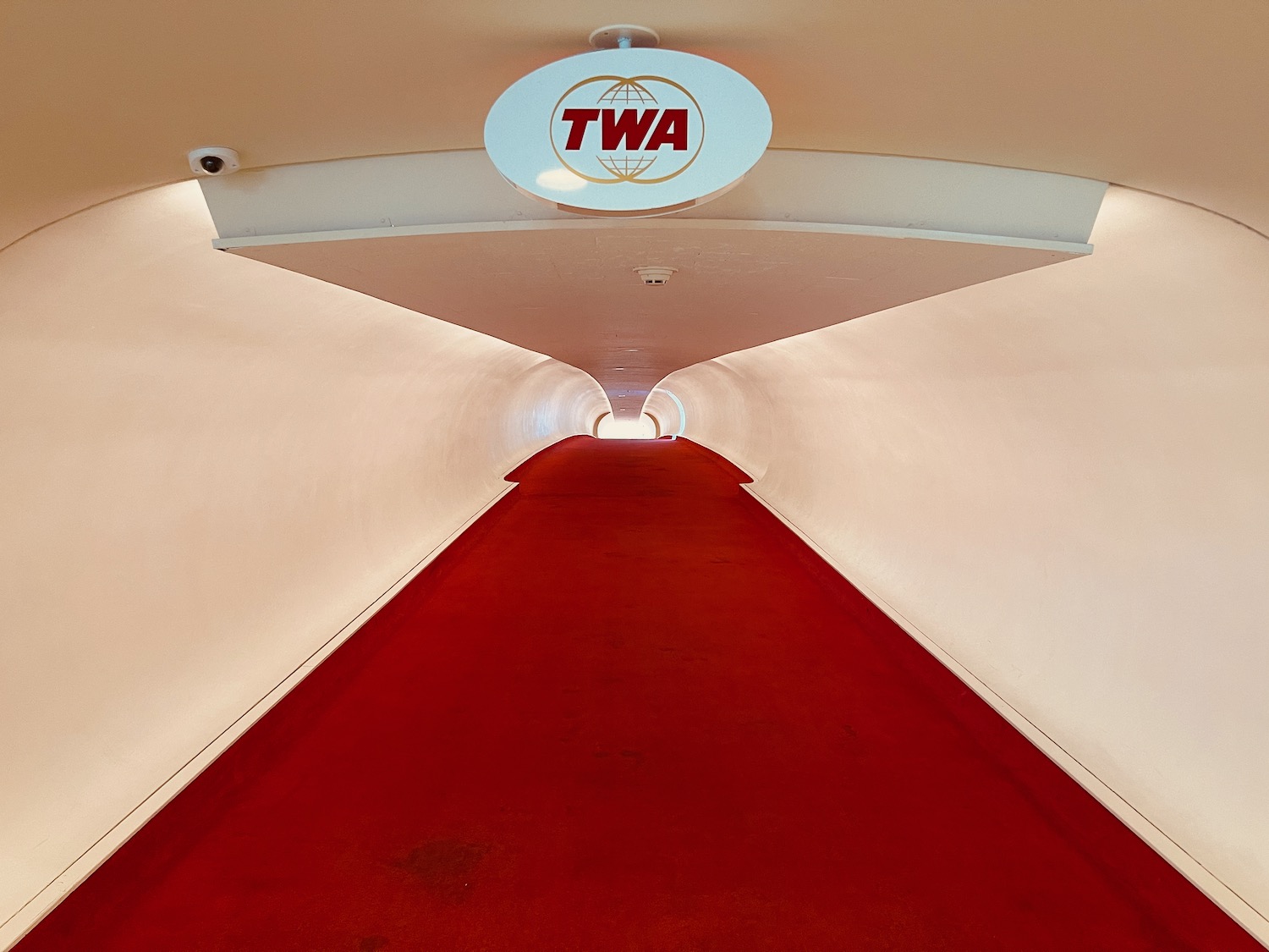 a red carpeted hallway with a sign on the ceiling