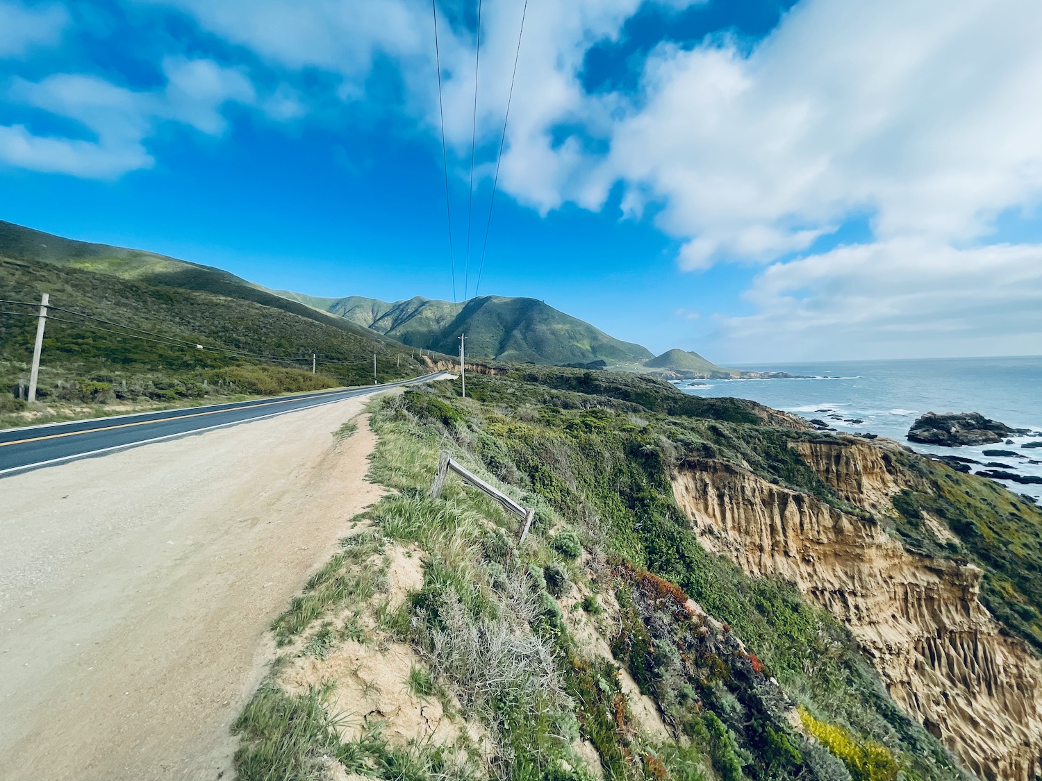 a road on a cliff with a body of water in the background