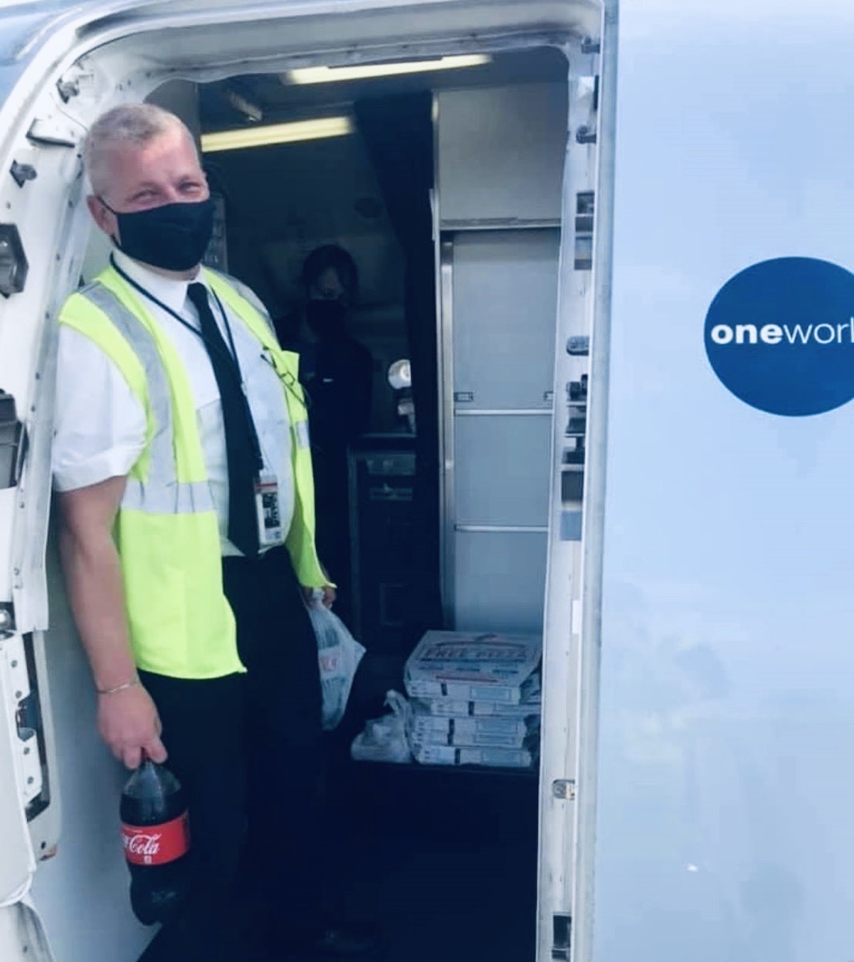 a man wearing a face mask and holding a bottle in a white airplane
