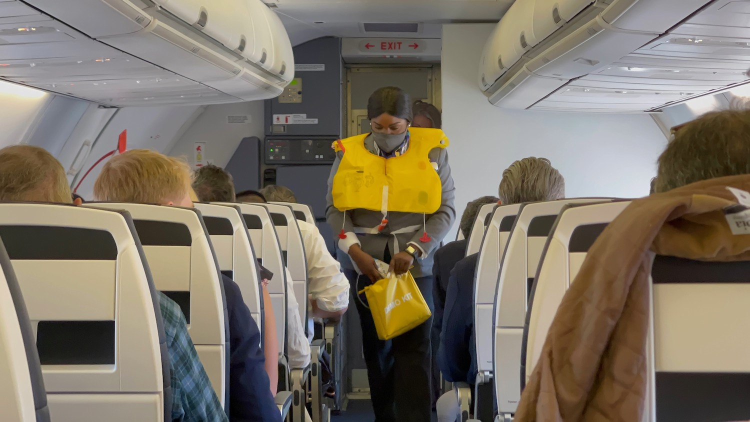a person wearing a mask and a yellow life jacket standing in an airplane