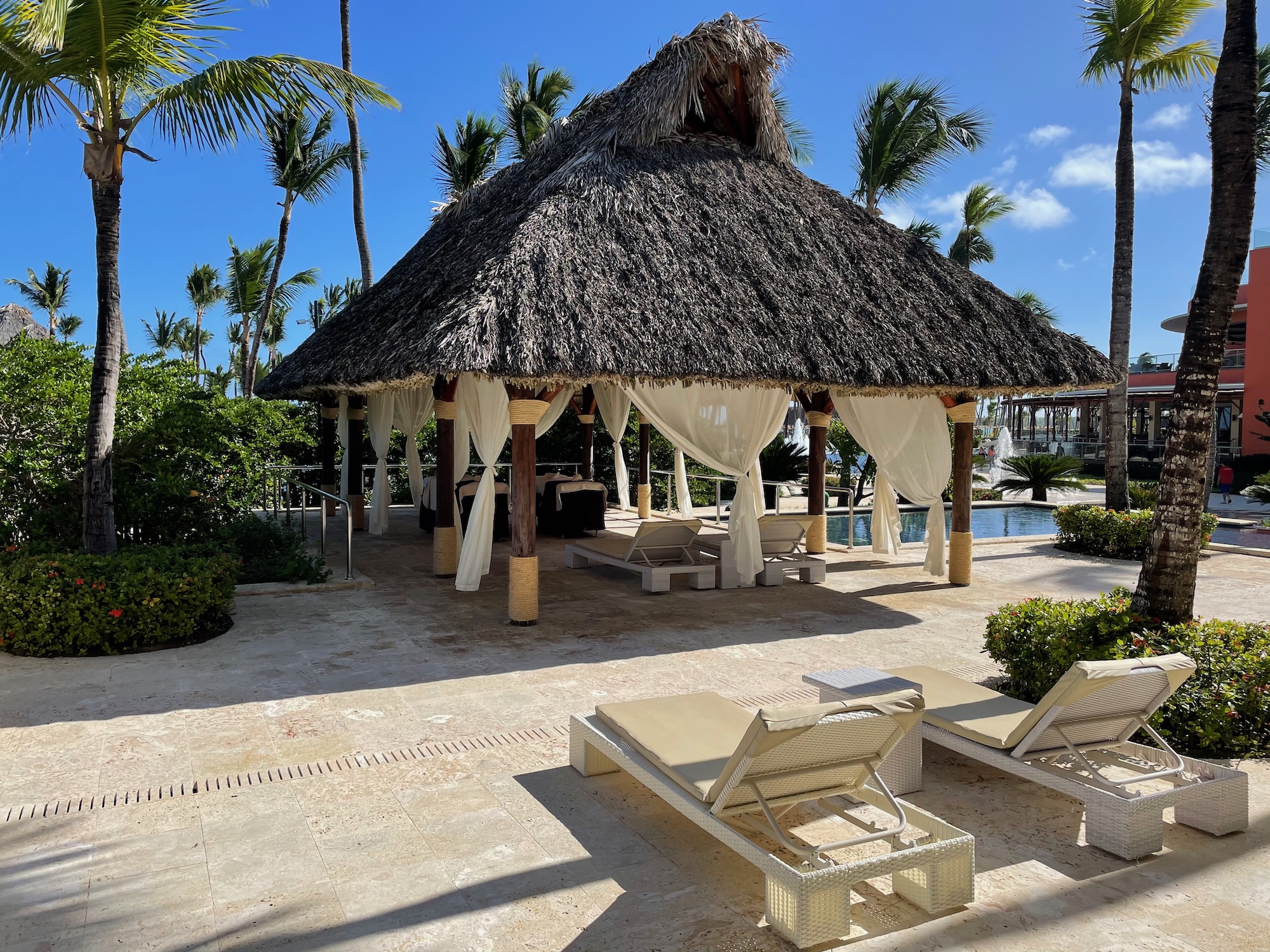 a hut with a thatched roof and lounge chairs