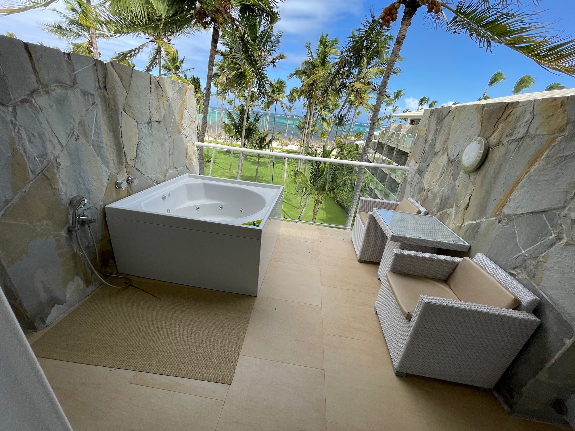 a bathtub and chairs on a balcony