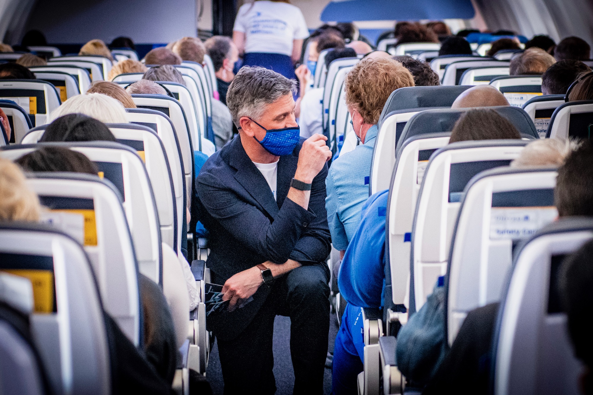 a man wearing a face mask sitting in an airplane