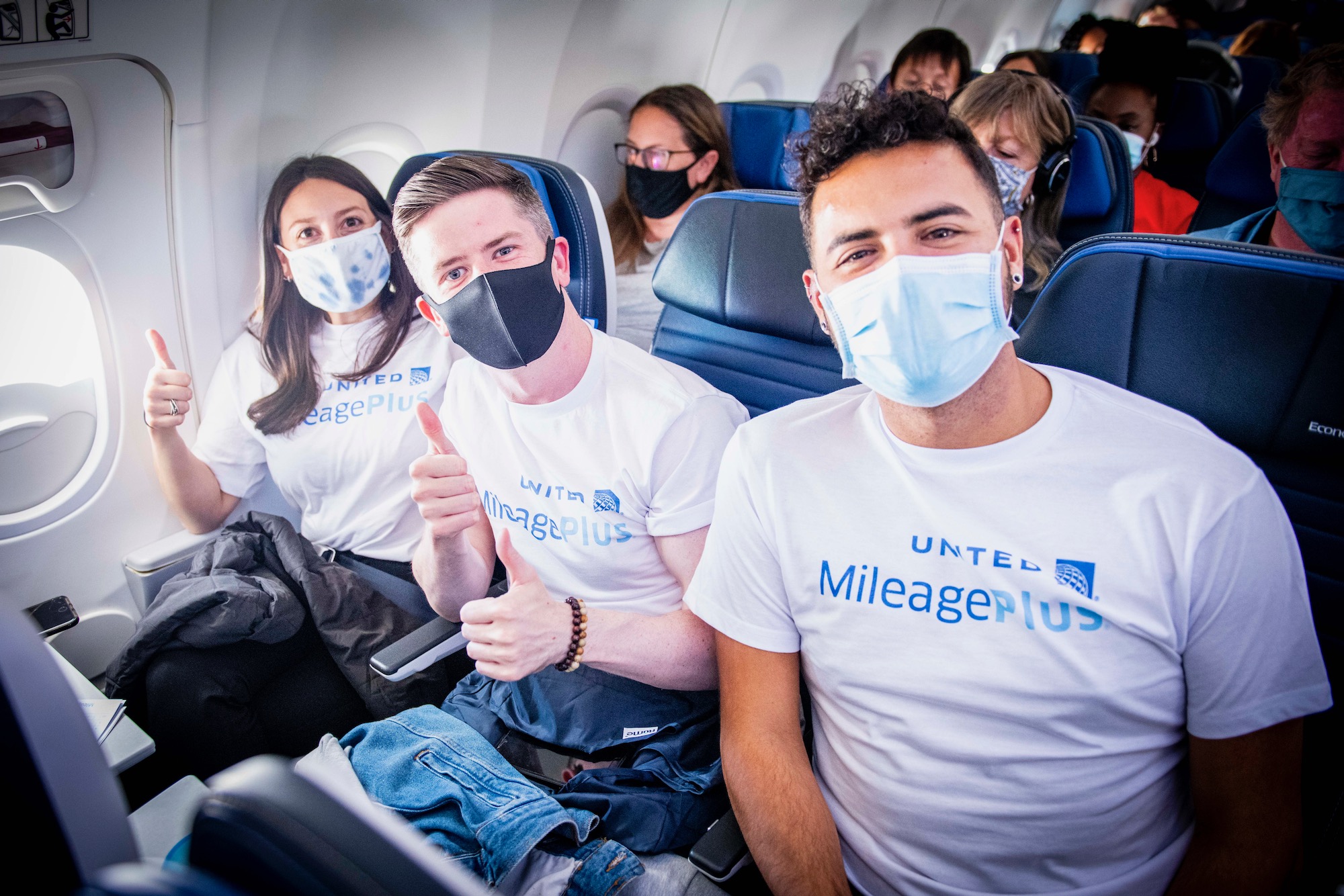 a group of people wearing face masks on an airplane