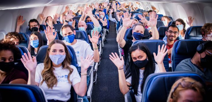 a group of people in a plane with their hands up