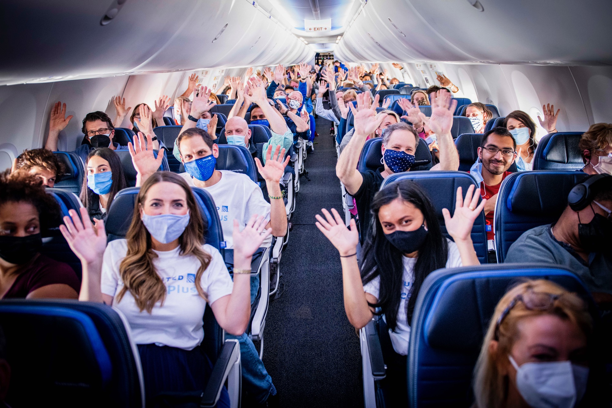 a group of people in a plane with their hands up