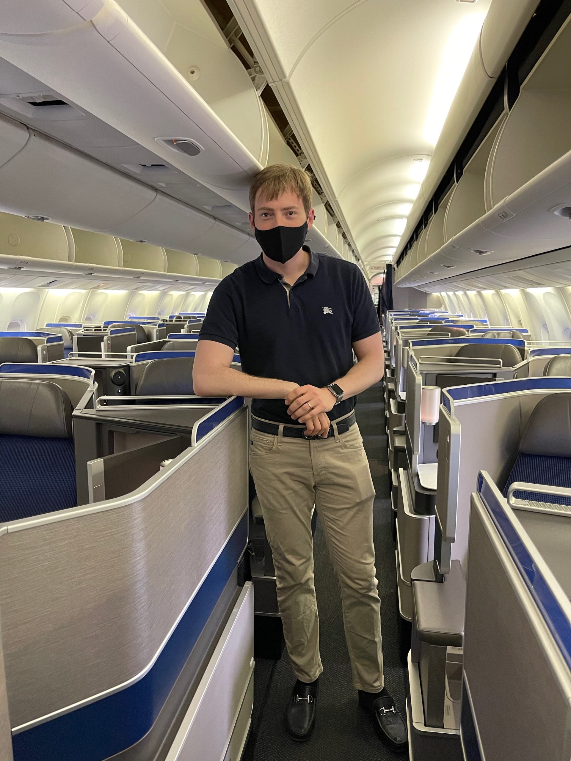 a man wearing a face mask standing in an airplane