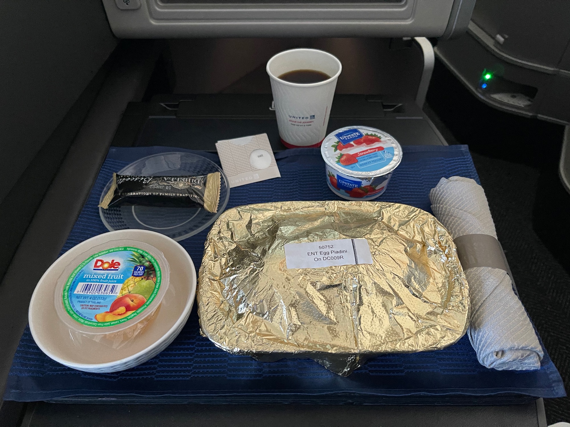 food on a tray with a paper towel and a cup of coffee