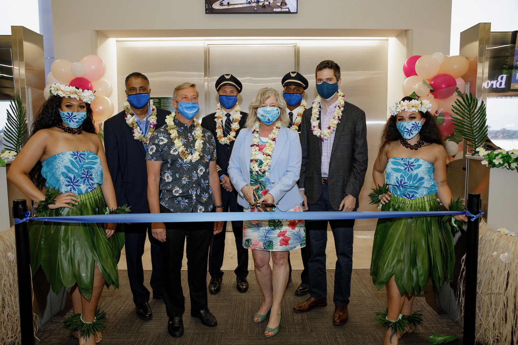 a group of people wearing face masks and standing in front of a ribbon