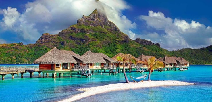 a group of houses on water with a hammock in front of Bora Bora