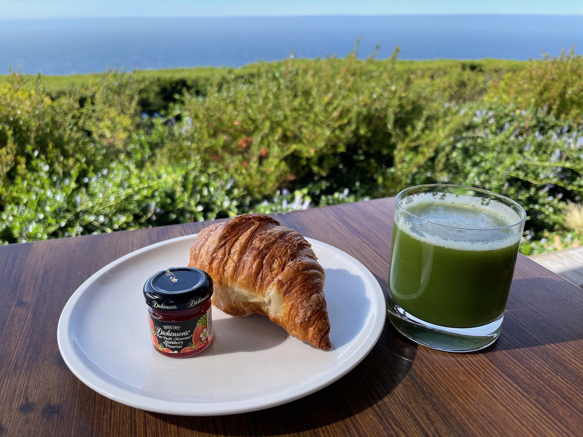 a croissant and jam on a plate with a glass of juice on a table