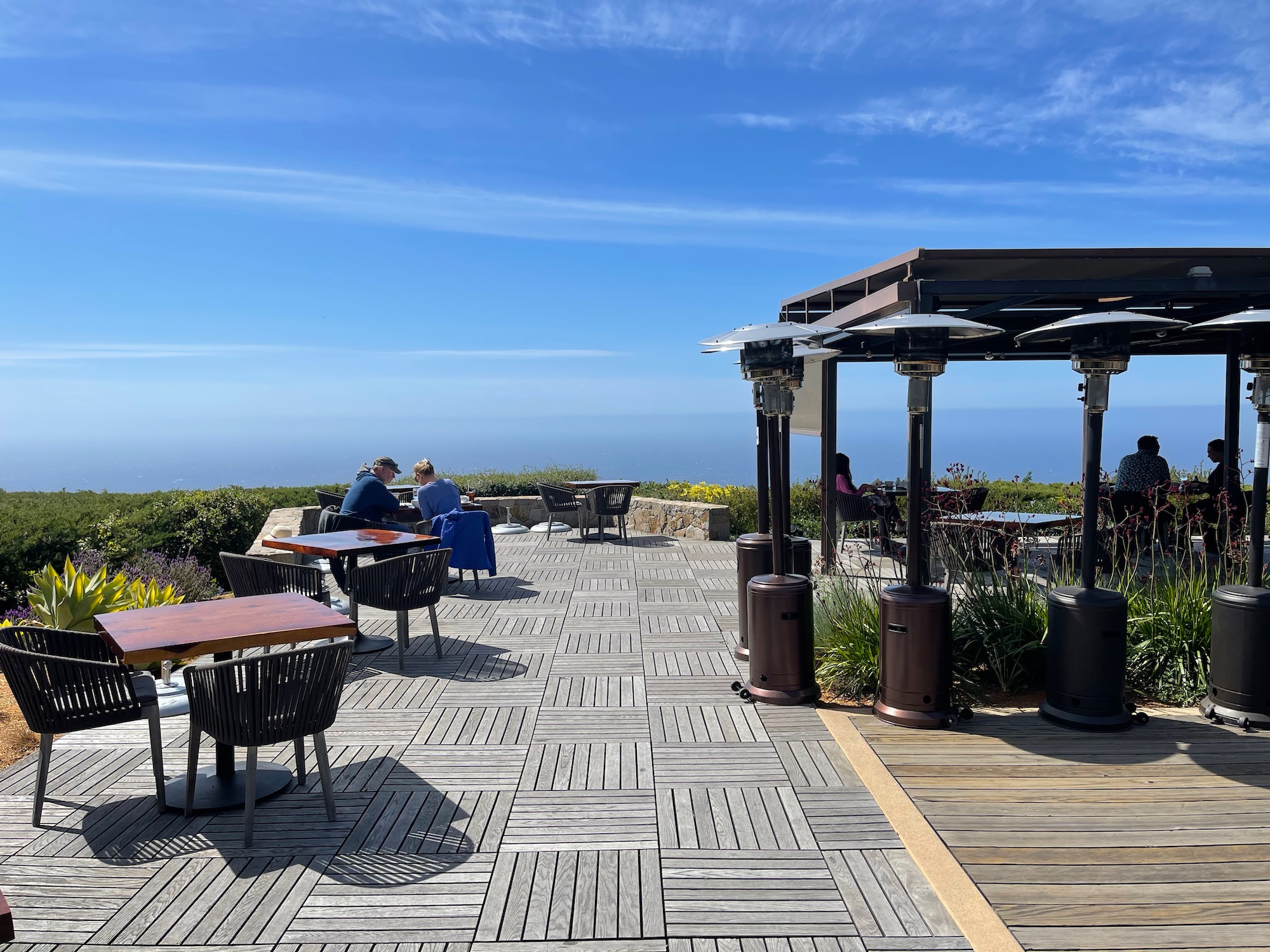 a group of people sitting at tables on a wooden deck