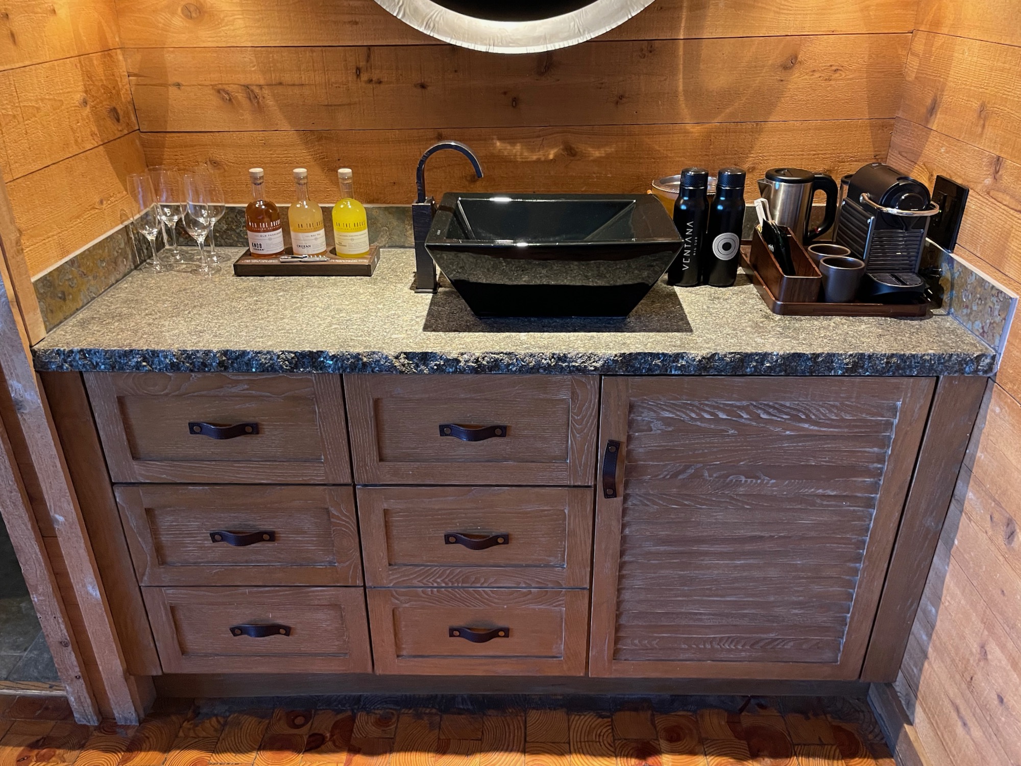 a counter top with a sink and bottles of wine