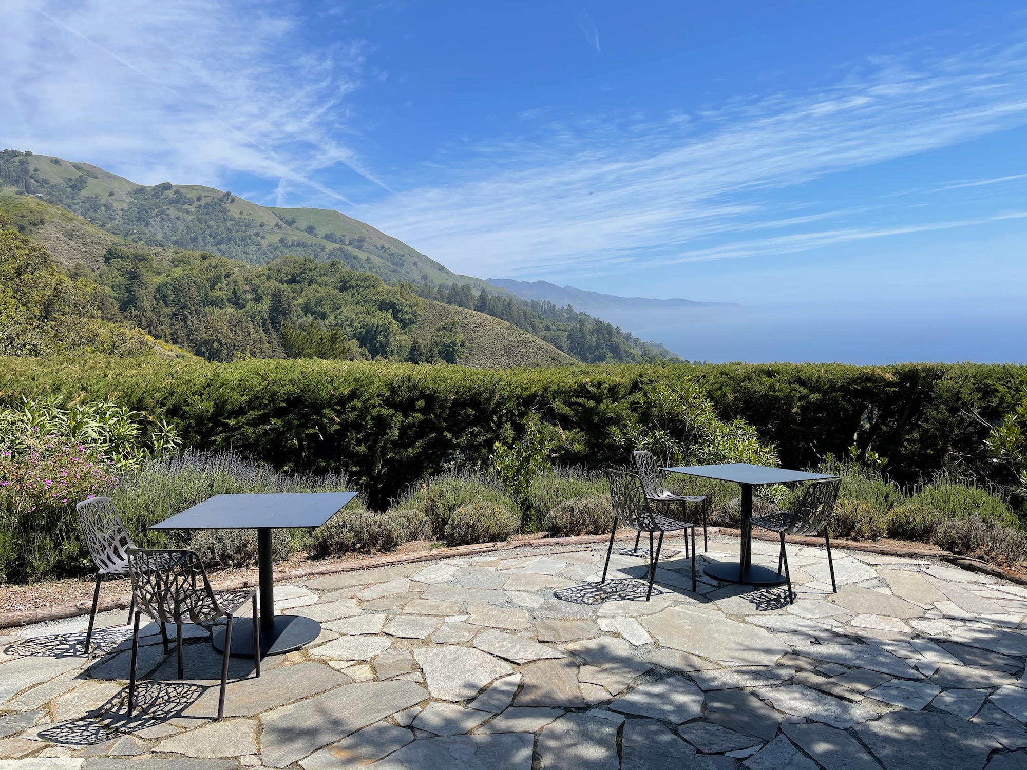 a table and chairs on a stone patio with a hill in the background