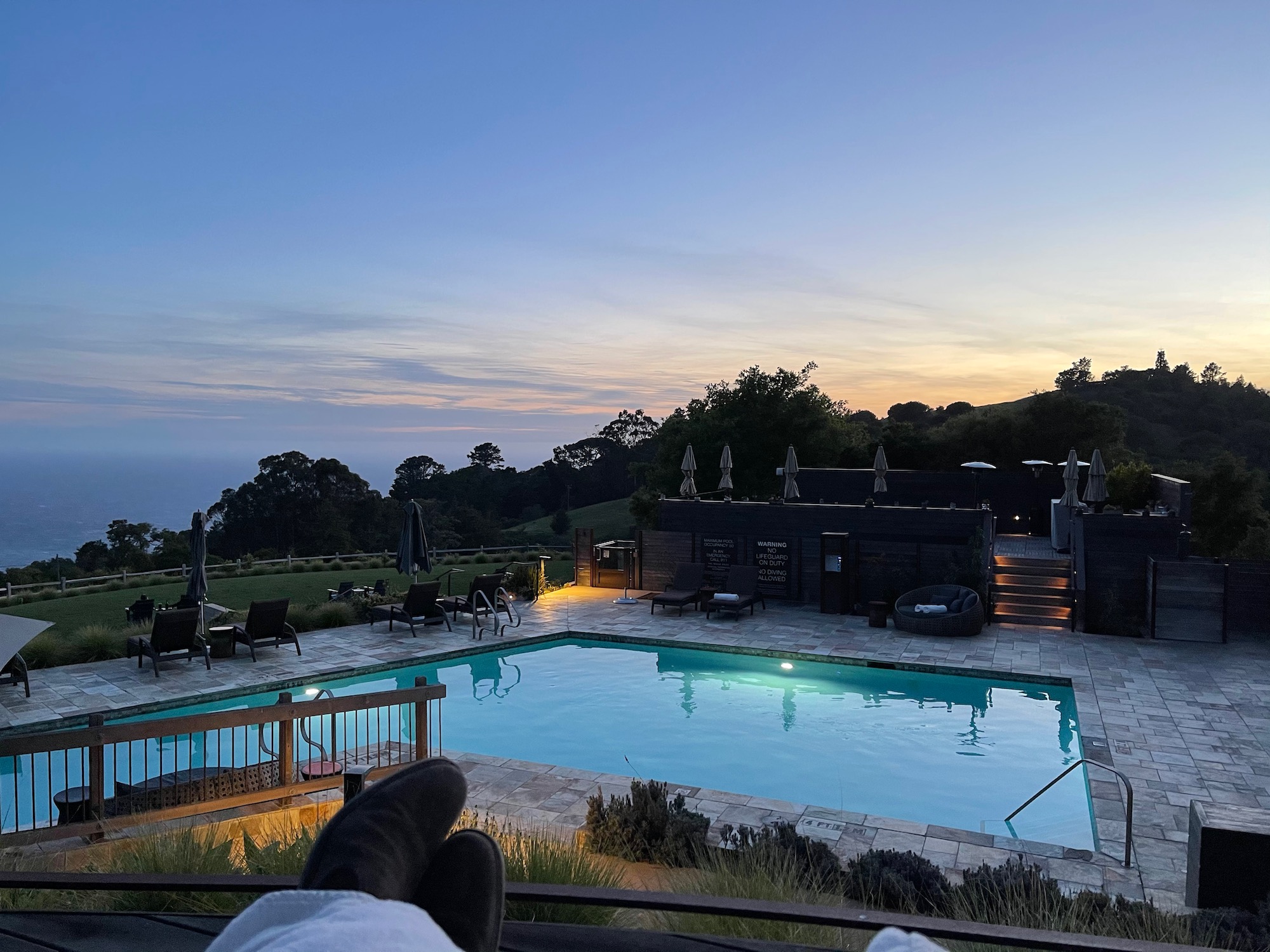 a pool with a deck and chairs in the back