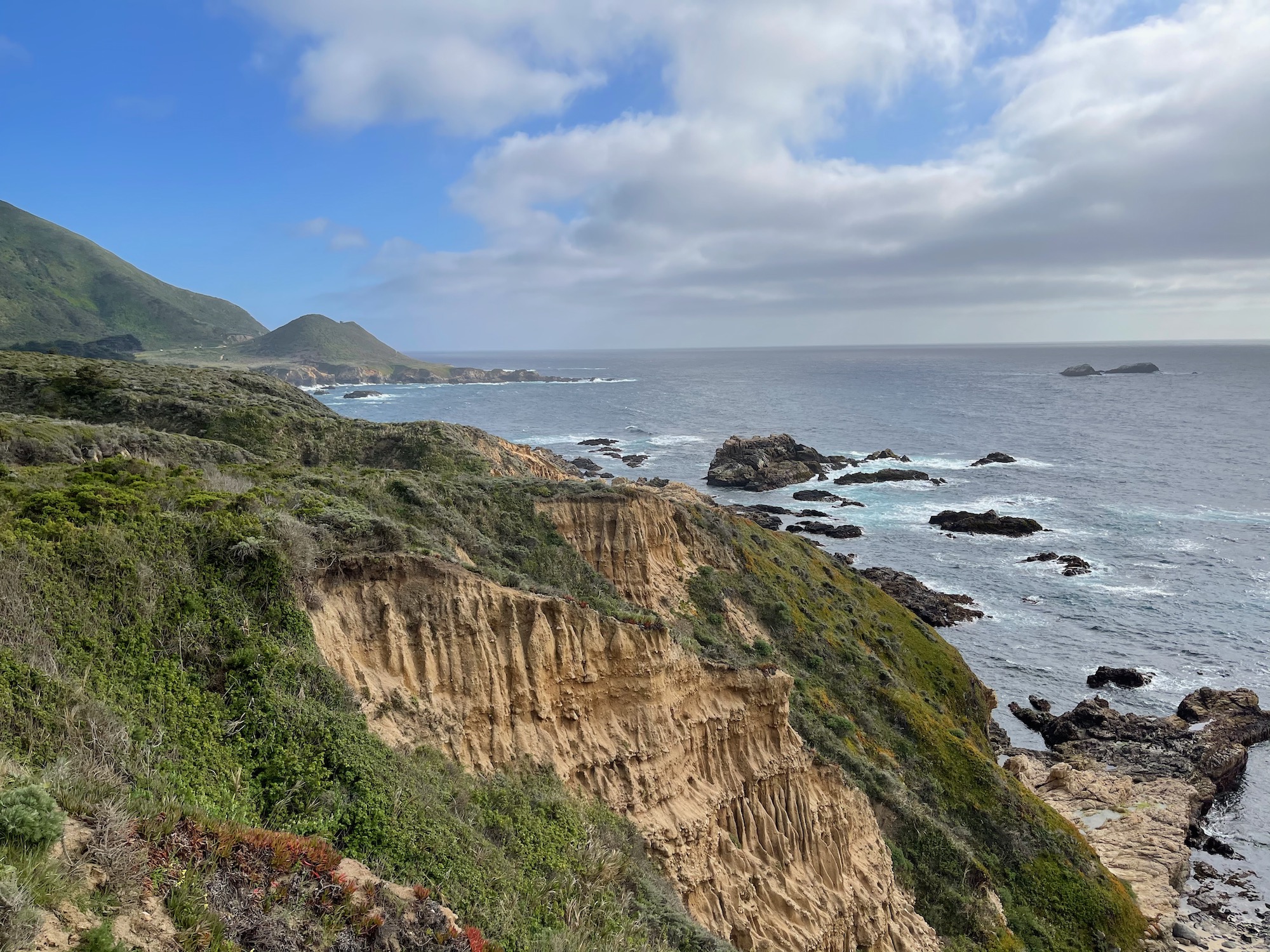 a cliff with grass and rocks by the ocean