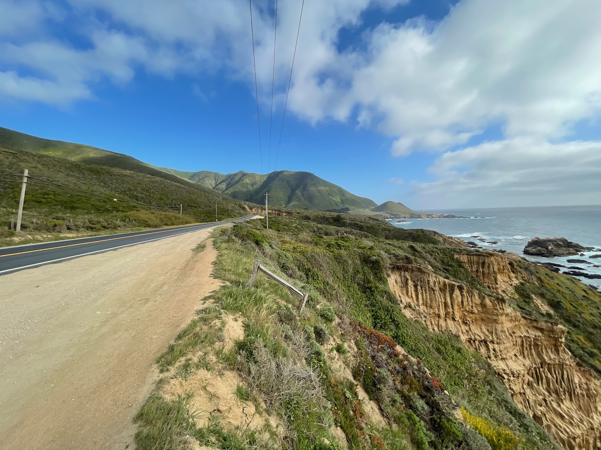 a road on a cliff with a body of water in the background