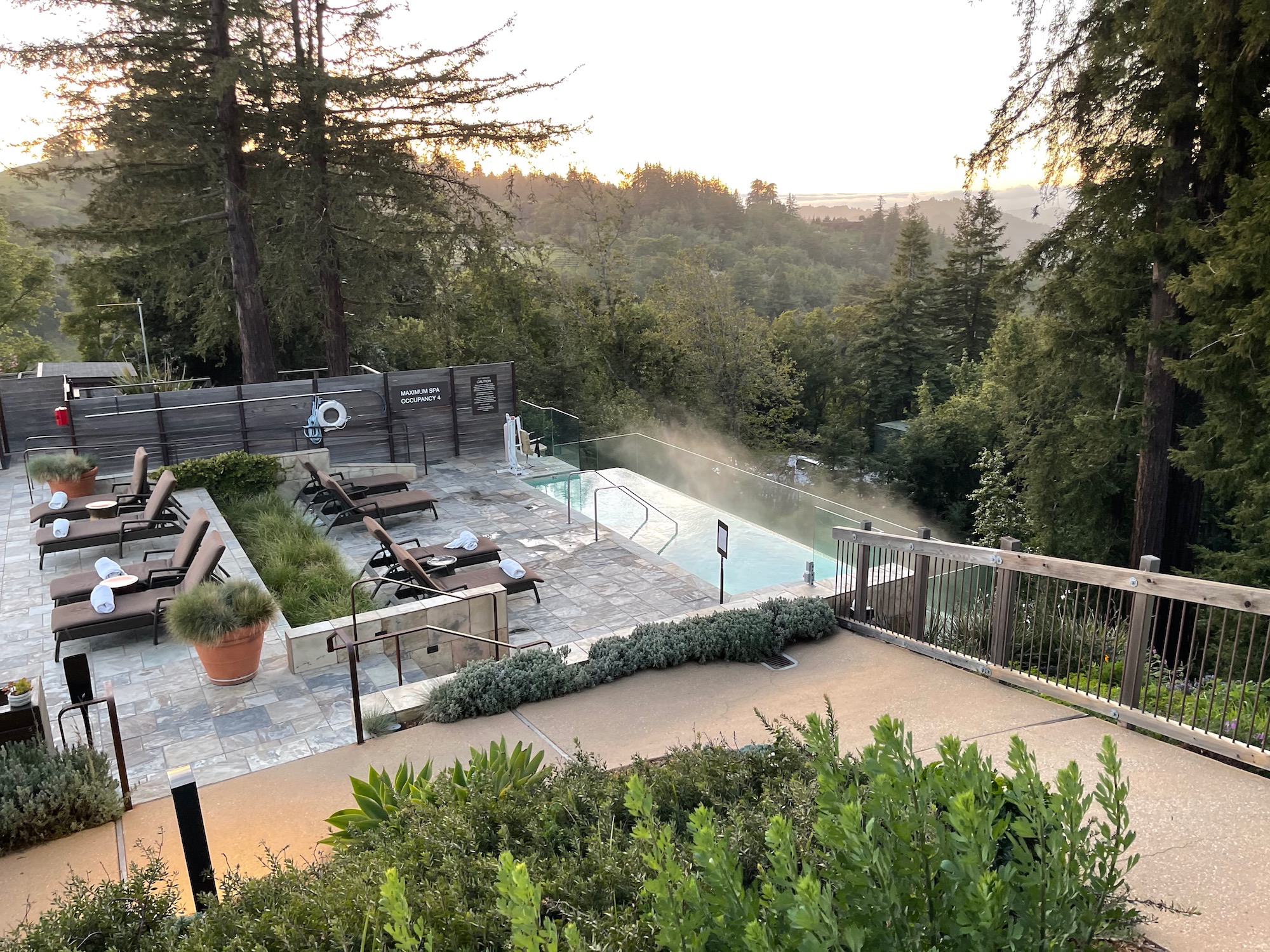 a pool with a deck and chairs and trees