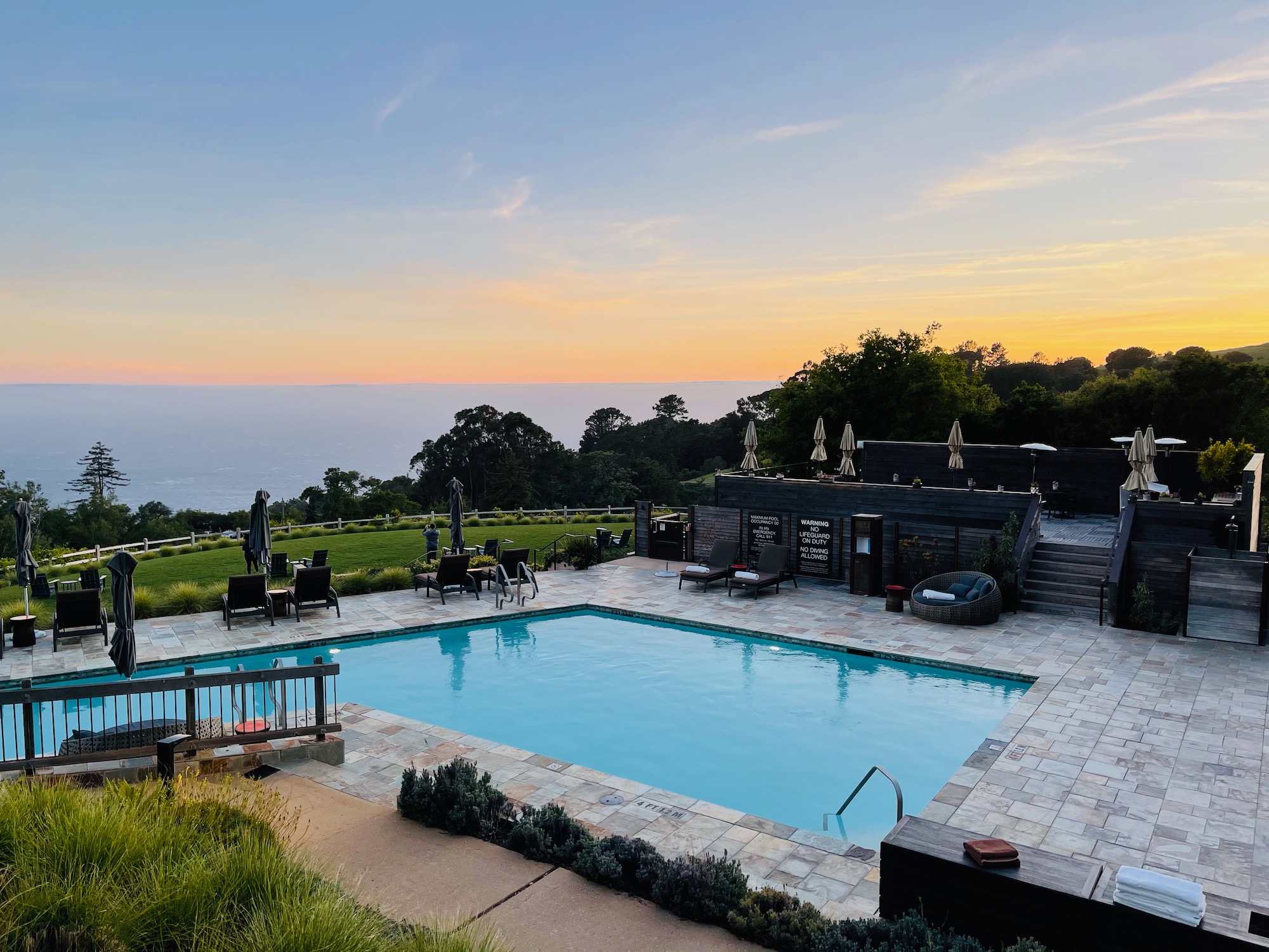 a pool with chairs and a deck overlooking a body of water