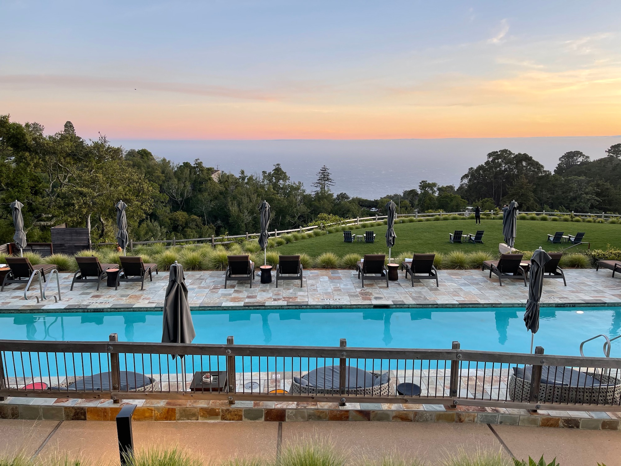 a pool with chairs and umbrellas and a view of the ocean