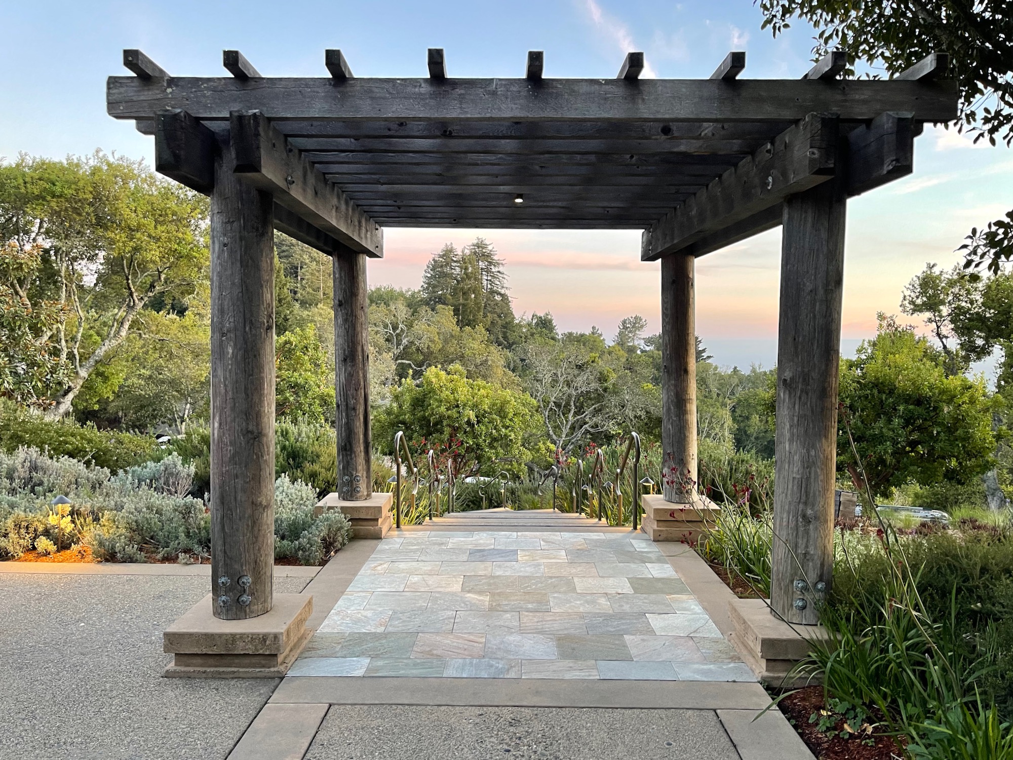 a wooden structure with a stone walkway and trees in the background