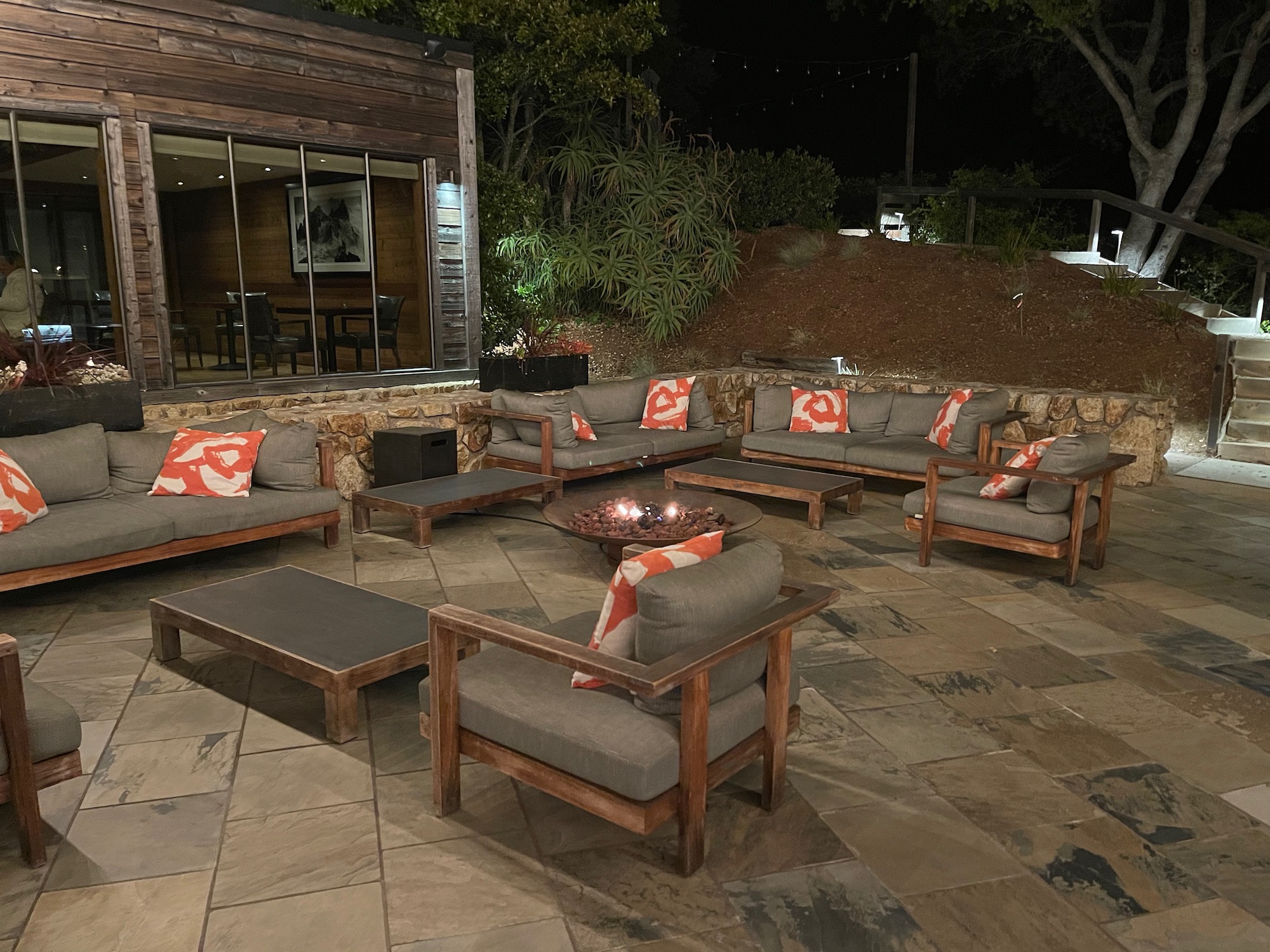 a patio with a fire pit and chairs