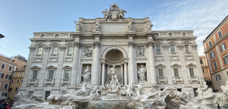 a large stone building with a fountain and statues with Trevi Fountain in the background