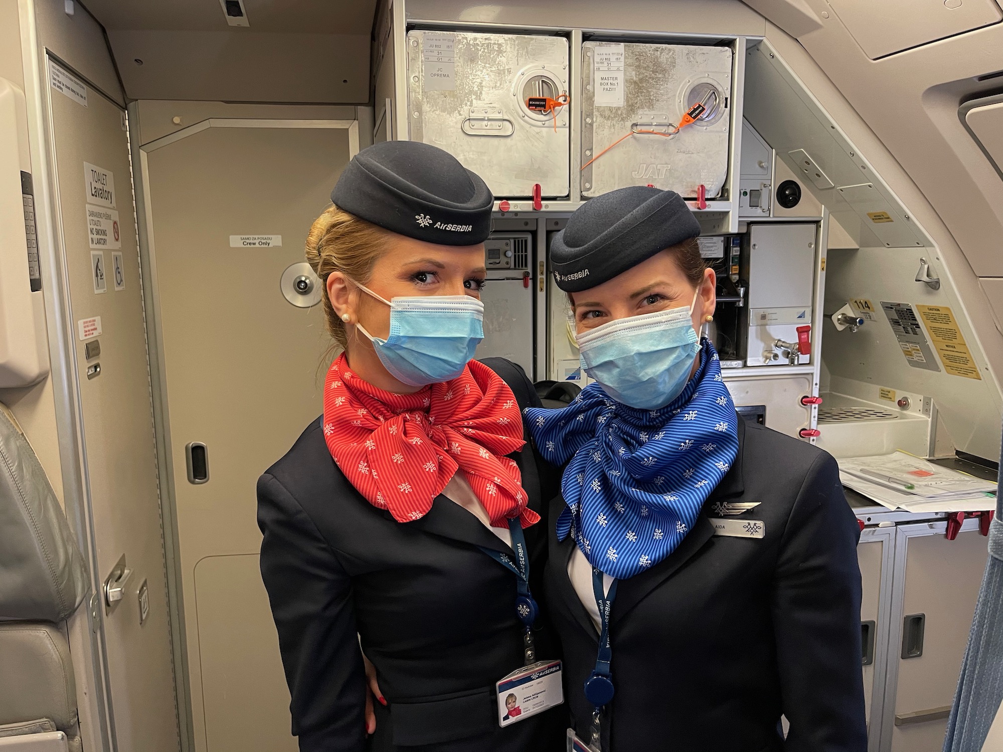 two women wearing masks and standing in a plane