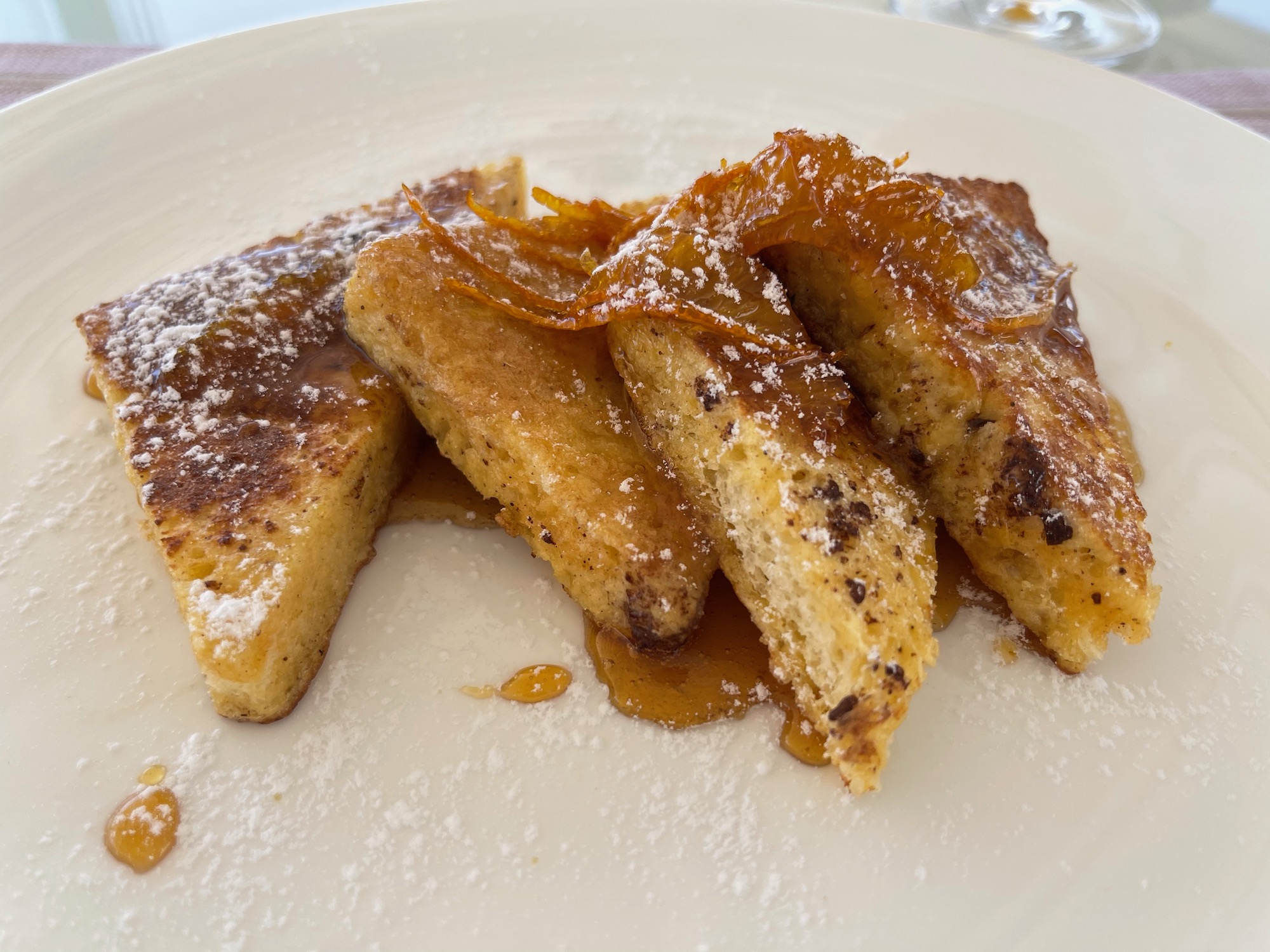 a plate of french toast with syrup and orange peel