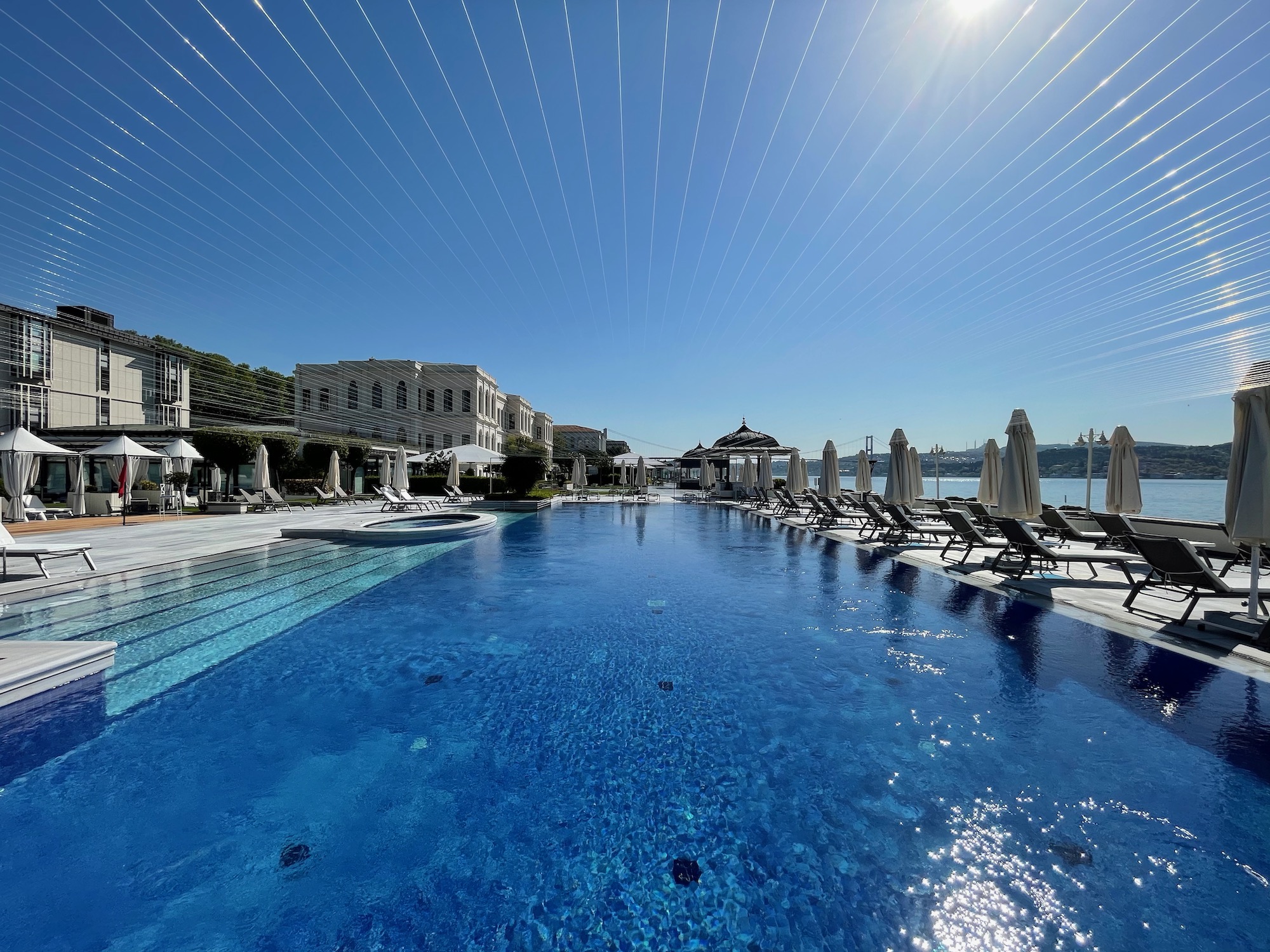 a pool with umbrellas and chairs in front of a building