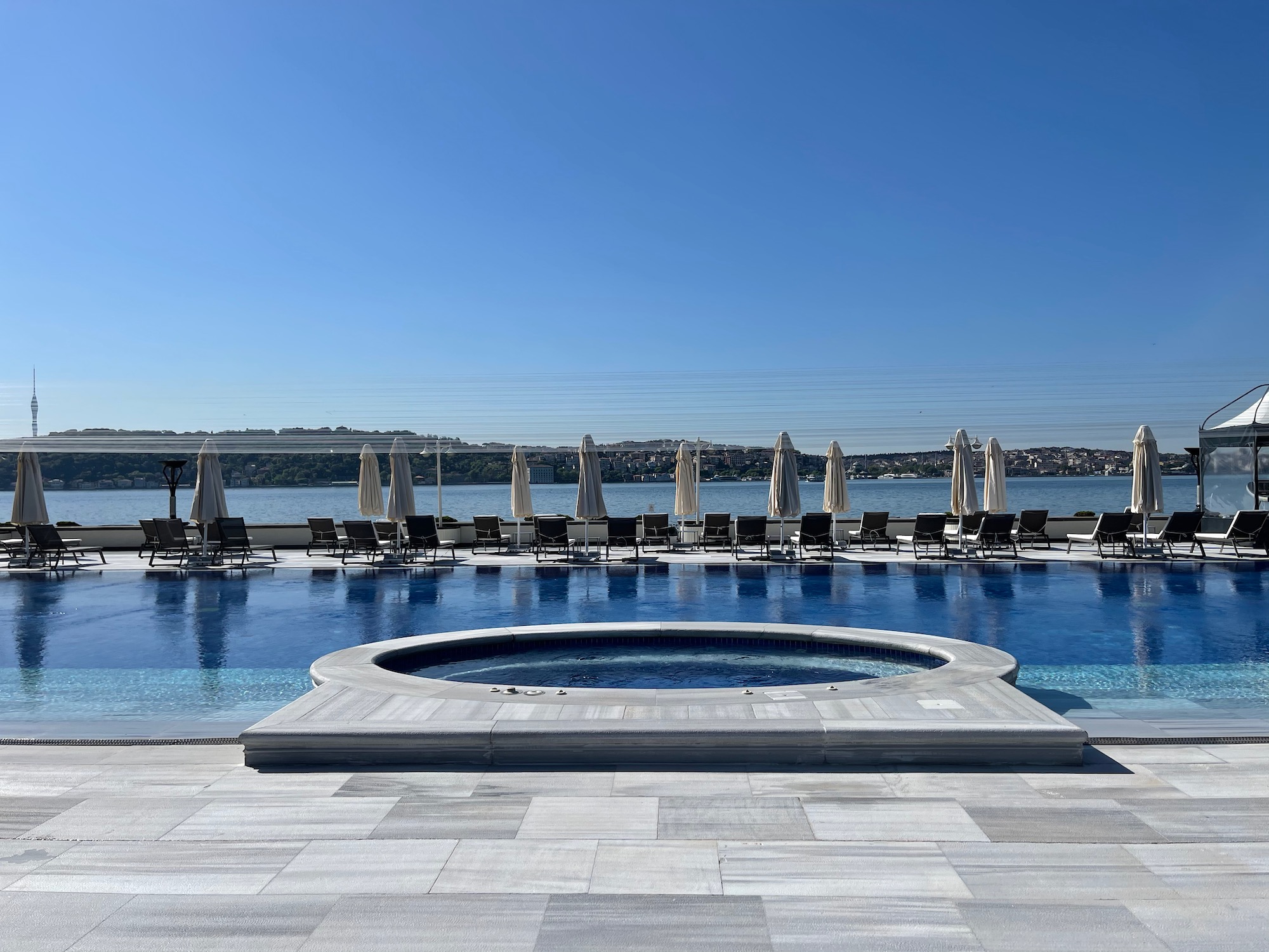 a pool with umbrellas and chairs by a body of water