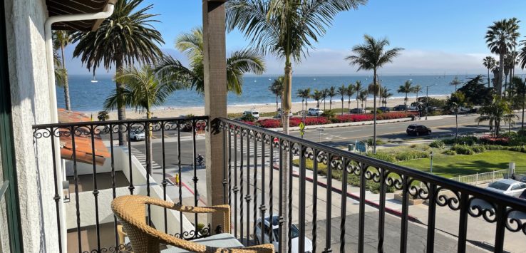 a balcony with a chair and a railing overlooking the ocean