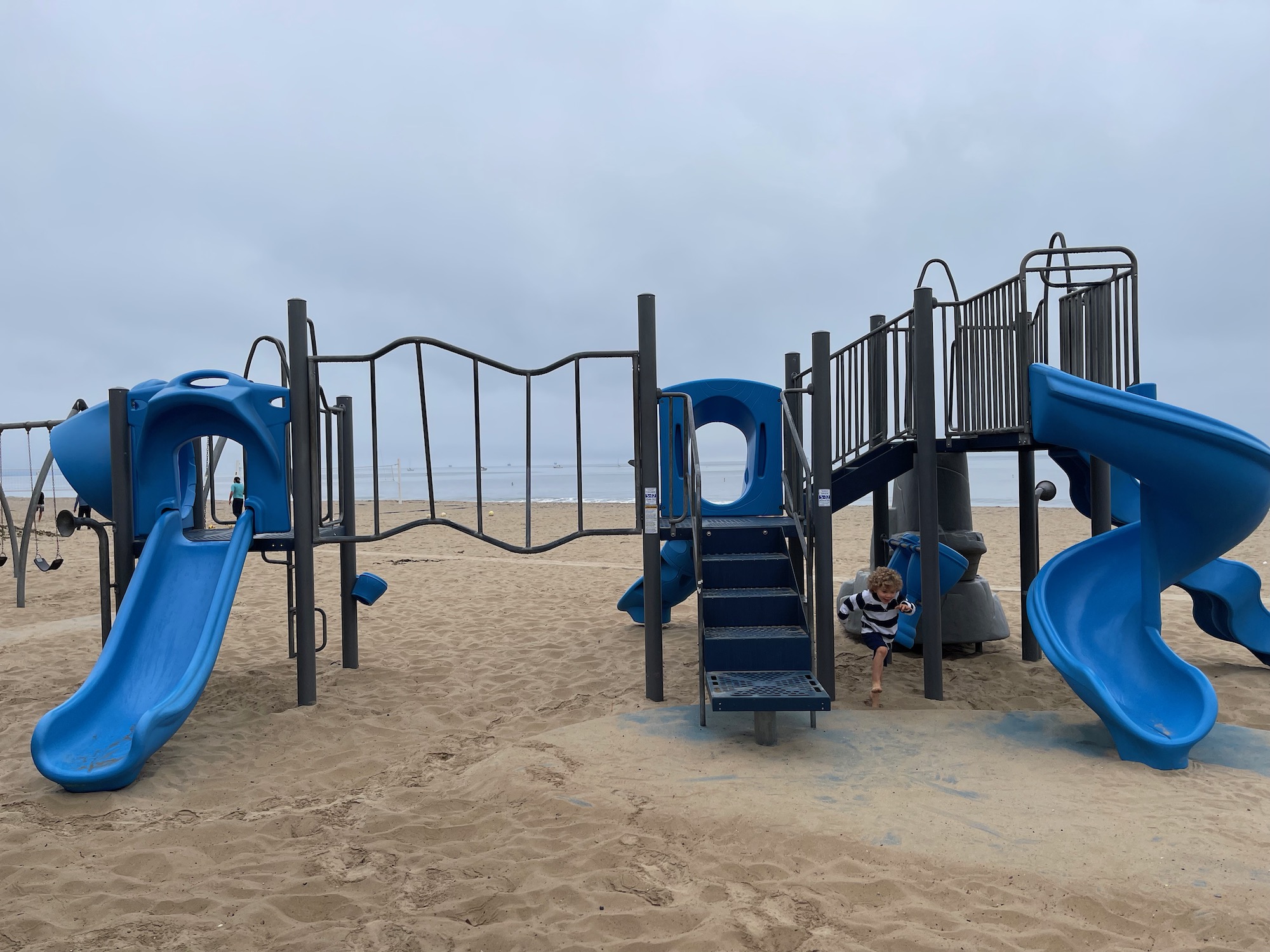 a playground with blue slides and a beach
