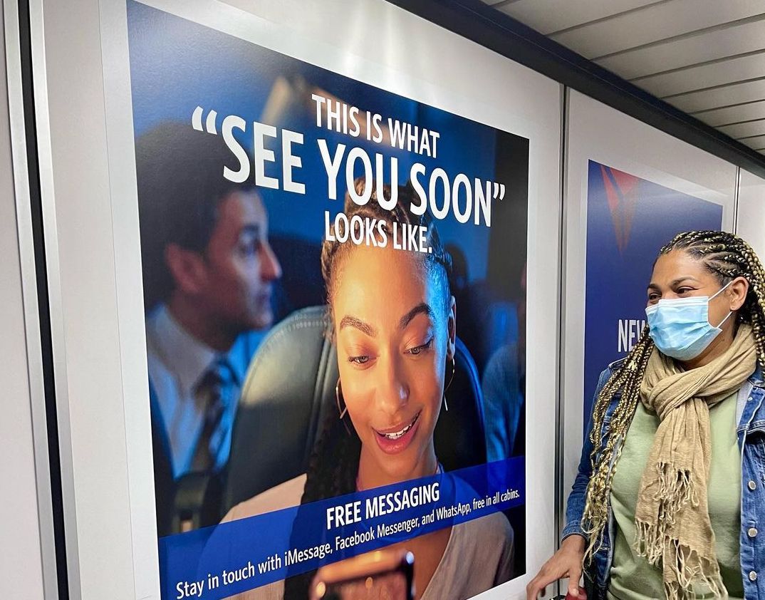 a woman wearing a face mask standing in front of a sign