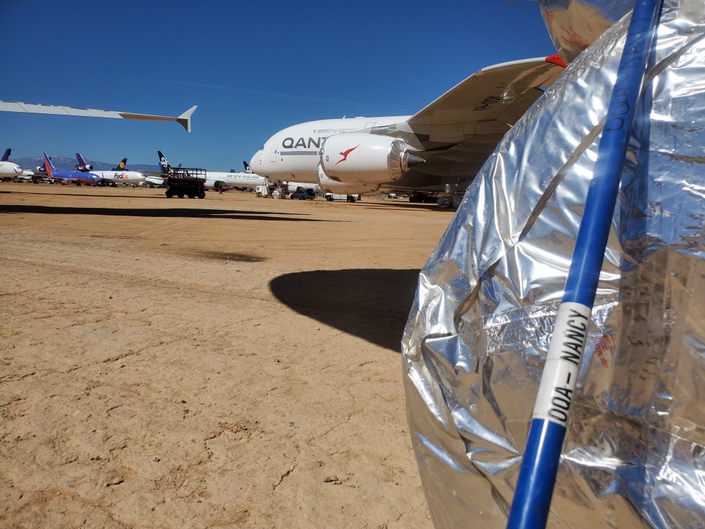 a group of airplanes on a dirt field