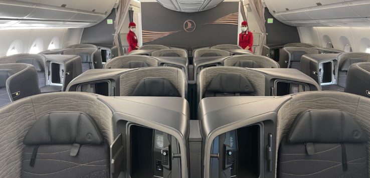 inside an airplane with seats and people in red uniforms