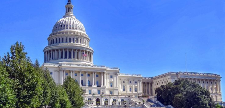 a large white building with a dome and a lawn with United States Capitol in the background