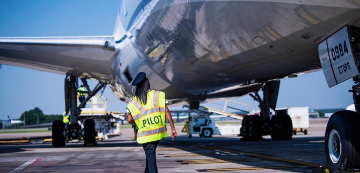 a person in a yellow vest walking next to an airplane