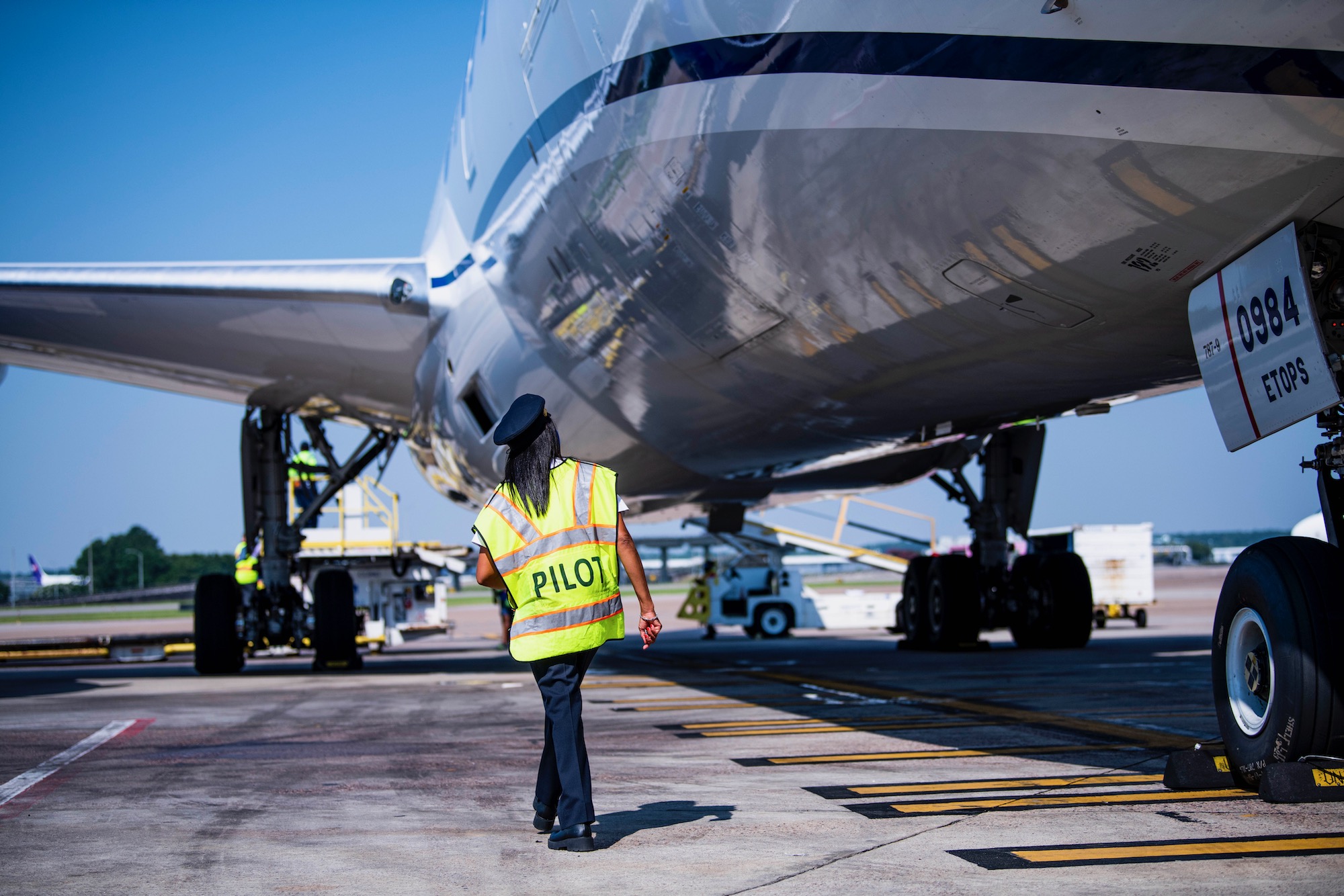 a person in a yellow vest walking next to an airplane